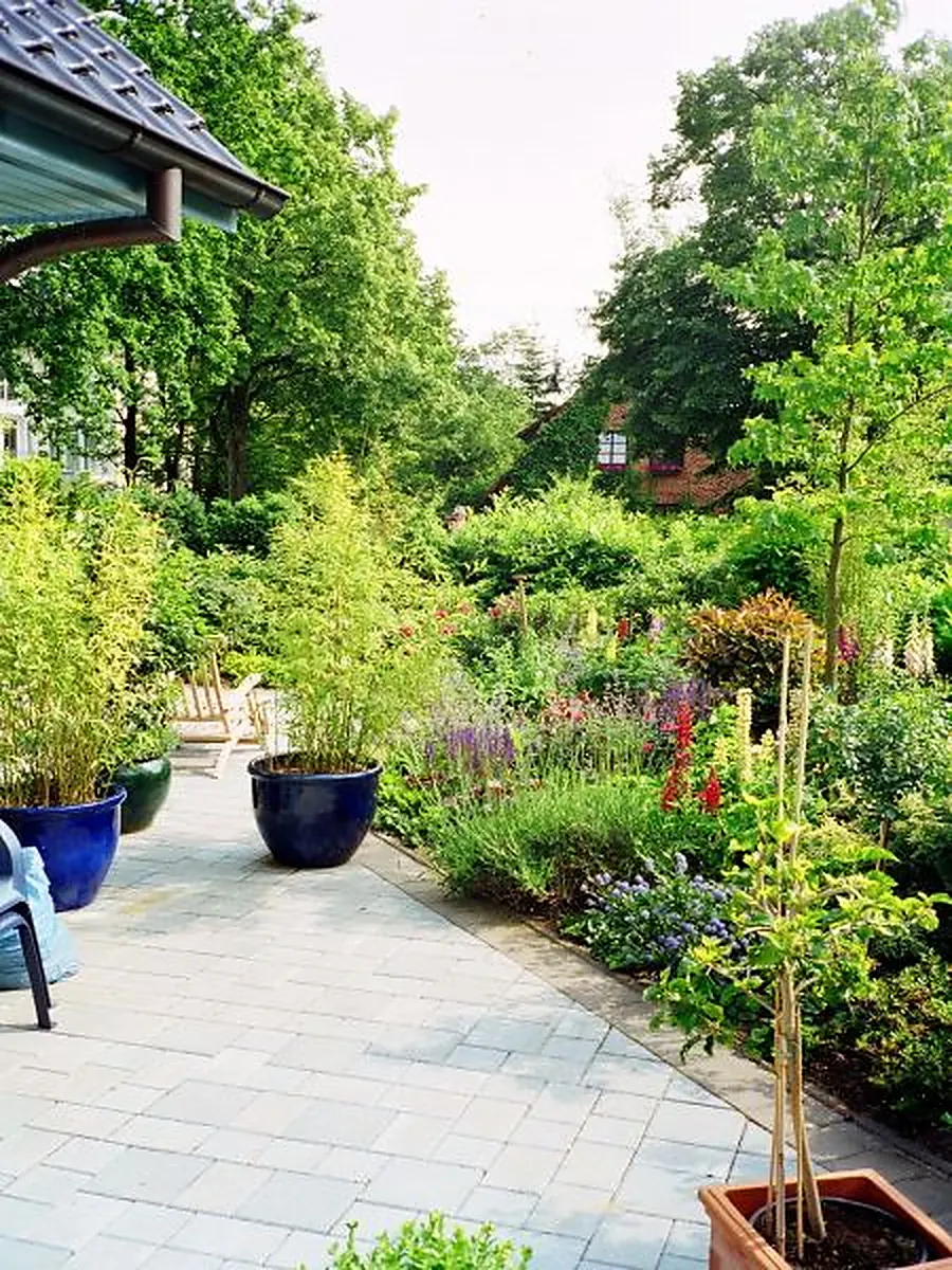 Gartenweg mit grauen Steinplatten und blauen Keramikkübeln