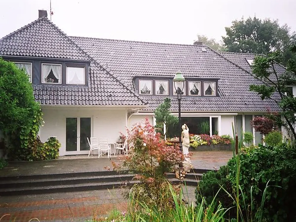 Einfamilienhaus mit Terrasse, Blumen und Gartenmöbeln